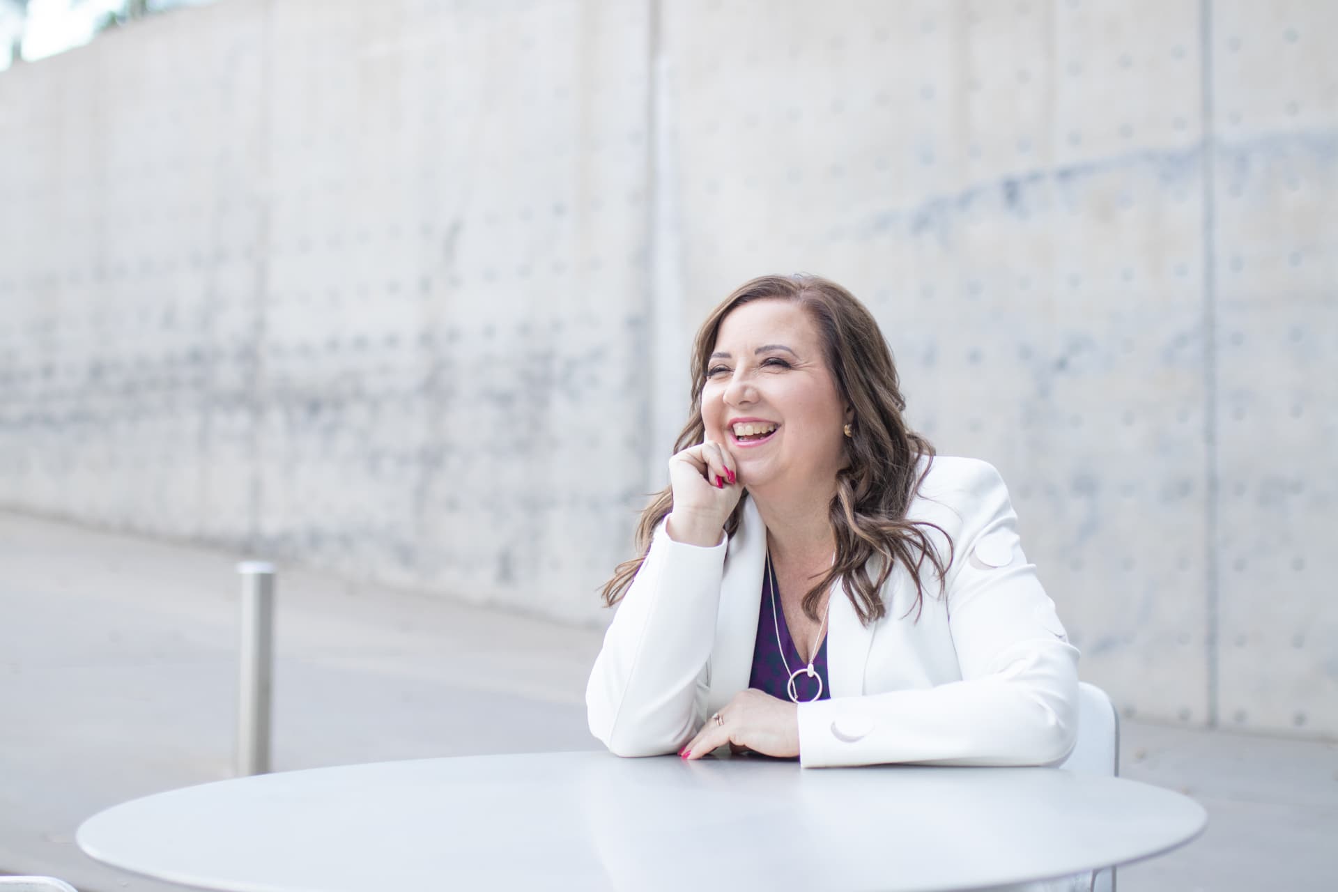 Deborah Daniel, CPA and wealth strategist, laughing at an outdoor table.